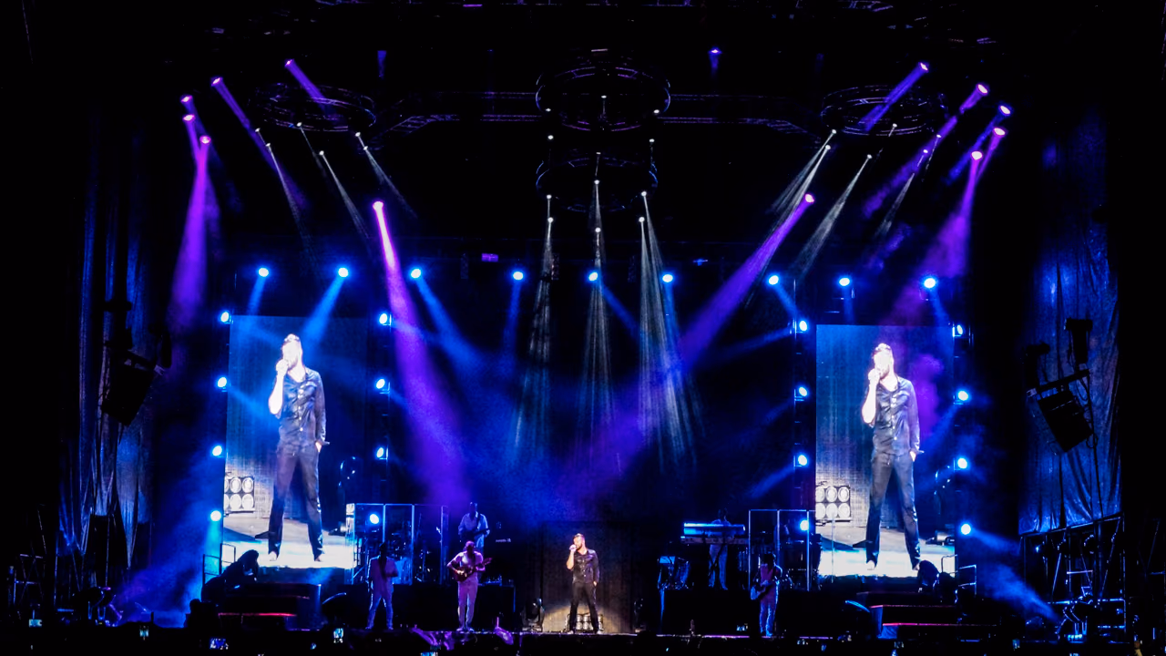 Escenario de concierto de Ricky Martin con pantallas laterales y haces de luz