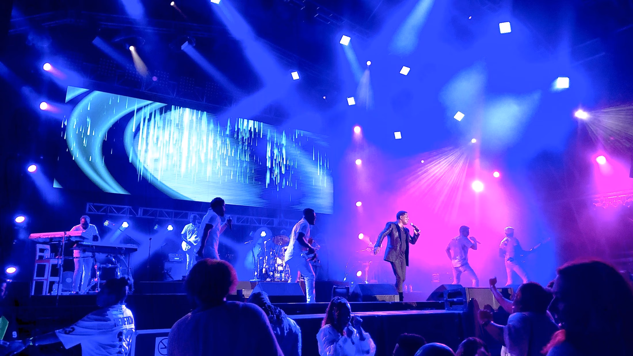 Escenario de Sol Fest Cancún con banda en vivo, pantalla LED y luz azul y magenta